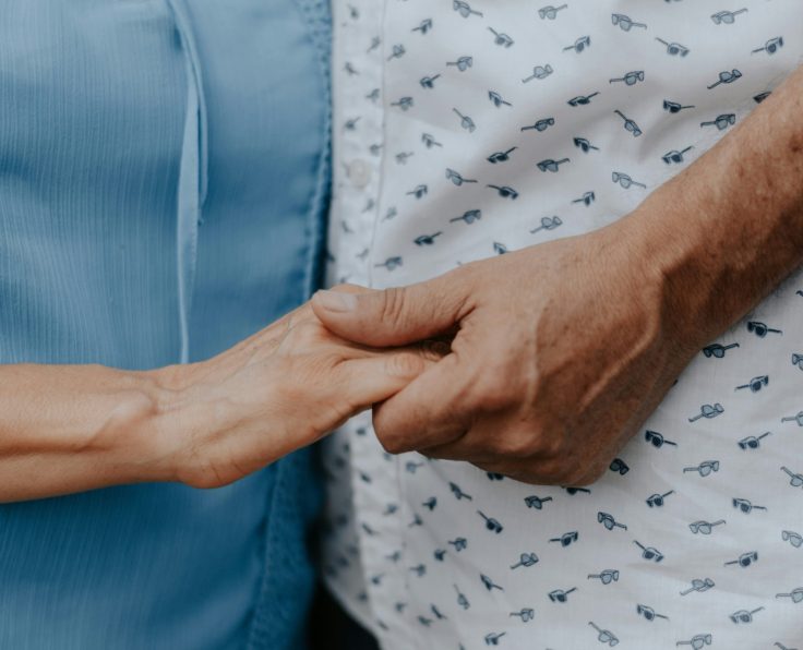 A patient and care giver holding hands.